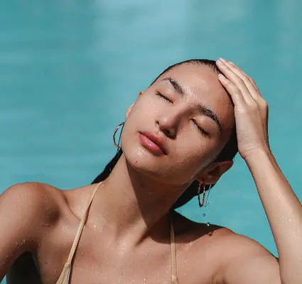 Woman relaxing in a pool with eyes closed and hand resting on her head