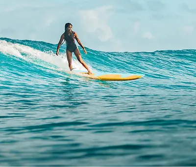 Surfer riding a turquoise wave on a yellow longboard