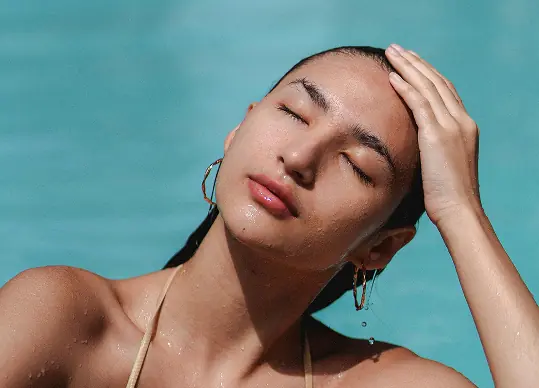 Woman relaxing in a pool with eyes closed and hand resting on her head