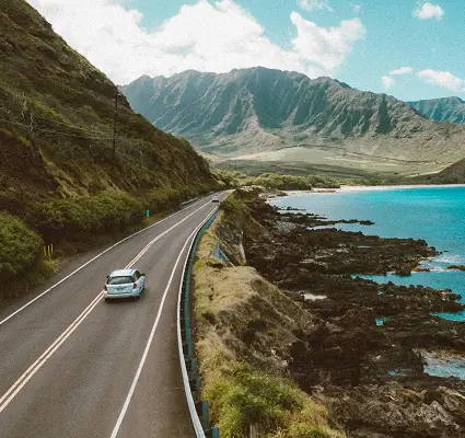 One car driving along a road over looking the sea