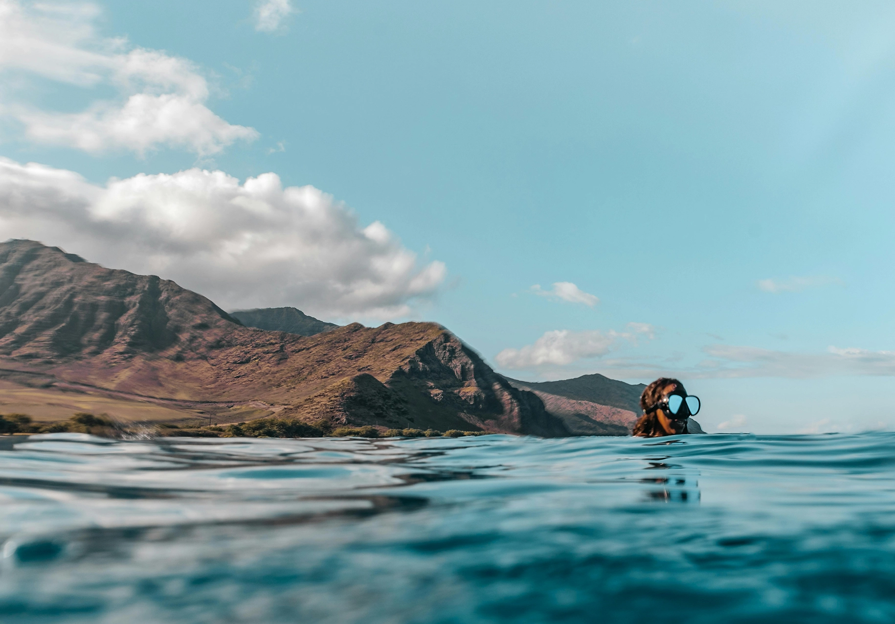 Snorkeler at the water’s surface with coastal mountains in the background